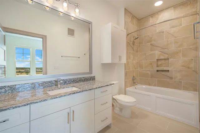 a bathroom with a granite countertop sink a toilet and bathtub