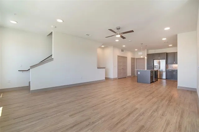 a view of a big room with wooden floor and a kitchen