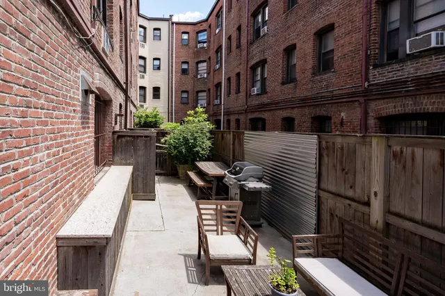 a view of a patio with a table and chairs and wooden fence