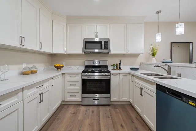 a kitchen with cabinets stainless steel appliances a sink and wooden floor