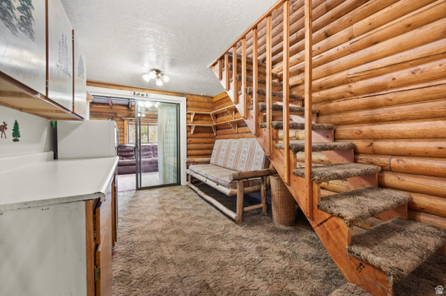 4725 Pine Ridge Road Evanston, UT 82930 - Photo 30 of 82 Natural wood log walls featuring a staircase with carpeted treads and a wooden railing