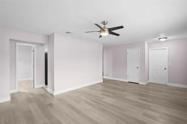 a view of empty room with wooden floor and ceiling fan