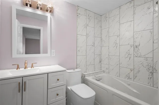 a bathroom with a toilet a sink a mirror a bathtub and shower