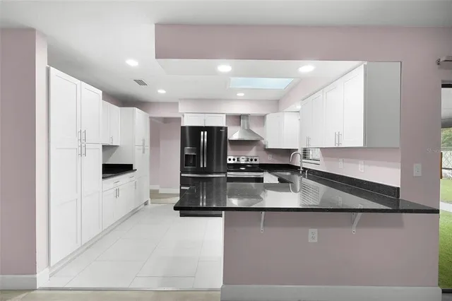 a large kitchen with stainless steel appliances a large counter top a stove and a refrigerator
