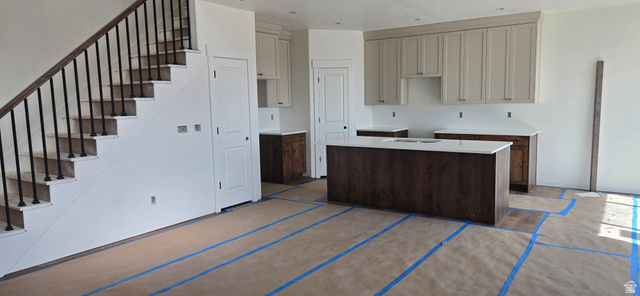 1651 West Ross Road Syracuse, UT 84075 - Photo 7 of 15 Kitchen with light countertops, a center island with sink, and dual tone cabinetry