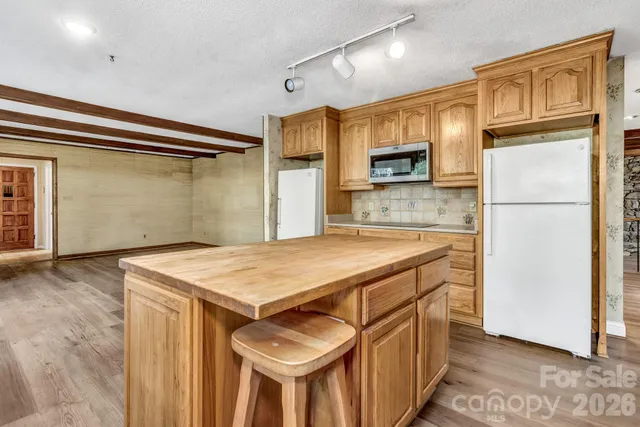 a kitchen with stainless steel appliances a stove a sink dishwasher a refrigerator and a microwave oven with wooden floor