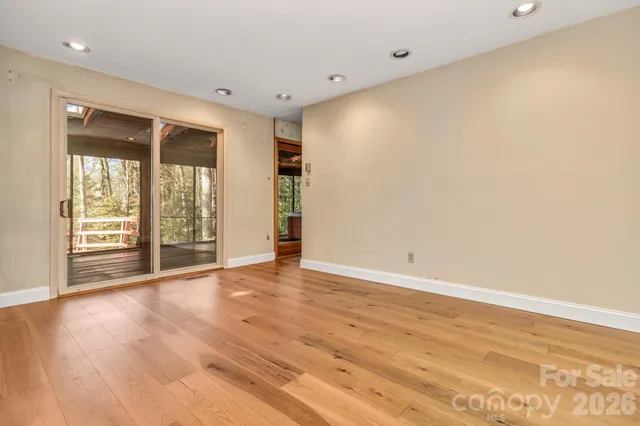 a view of an empty room with wooden floor and a fireplace