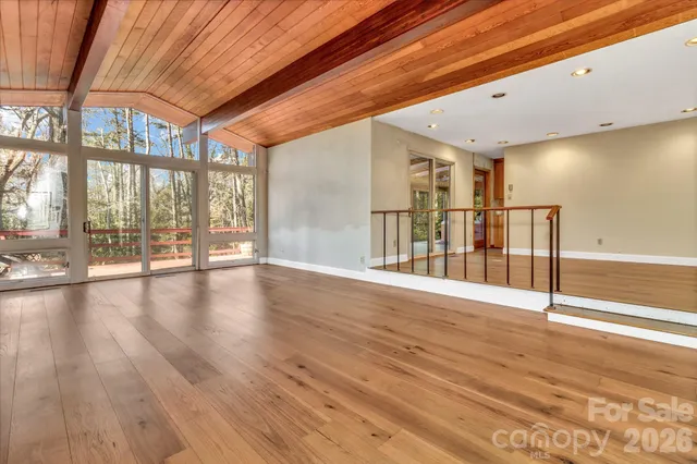 a view of an empty room with wooden floor fireplace and a window