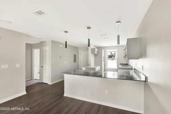 a large kitchen with stainless steel appliances a large counter top a wooden floor and a sink