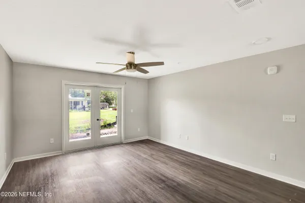 a view of an empty room with a window and wooden floor
