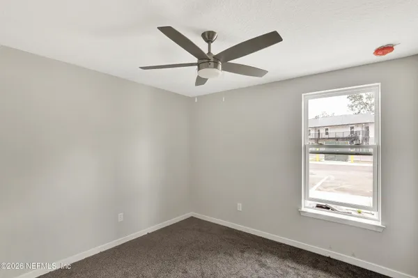 an empty room with ceiling fan and window