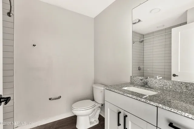 a bathroom with a granite countertop sink a toilet and a mirror