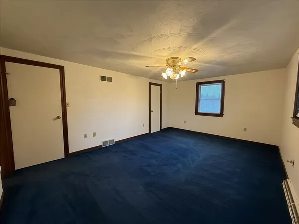 an empty room with a chandelier fan and windows