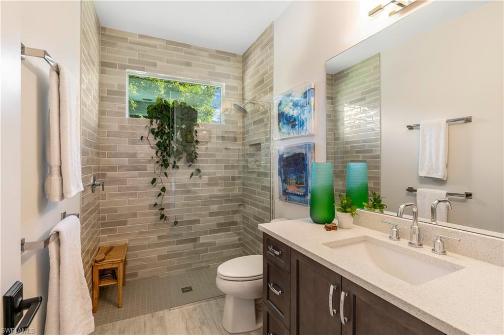 29 Johnnycake Drive Naples, FL 34110 - Photo 21 of 42 a bathroom with a granite countertop toilet a sink and a mirror