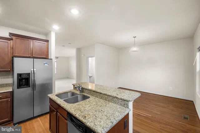 a kitchen with kitchen island granite countertop a sink and refrigerator