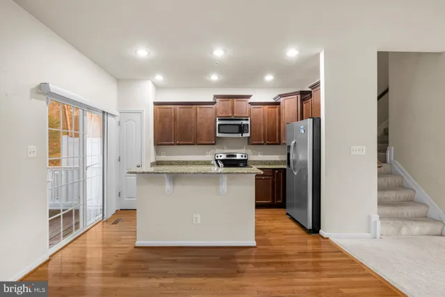 a kitchen with stainless steel appliances granite countertop a refrigerator a stove and a wooden floors