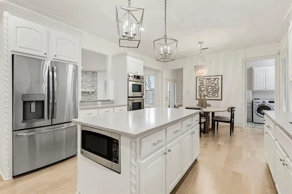 a kitchen with stainless steel appliances a kitchen island hardwood floor and a view of living room