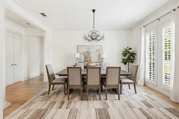 a dining room with wooden floor a chandelier a wooden table and chairs