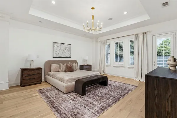 a spacious bedroom with a large bed a chandelier and windows