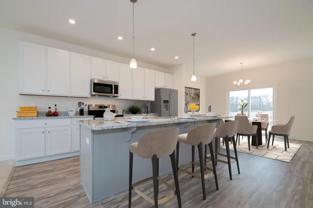 a kitchen with stainless steel appliances granite countertop a stove top oven a sink dishwasher a dining table and chairs with wooden floor