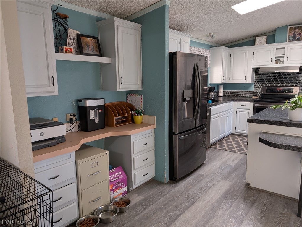 320 6th Street Panaca, NV 89042 - Photo 7 of 30 Kitchen featuring white cabinetry, stainless steel appliances, backsplash, light wood-type flooring, and crown molding