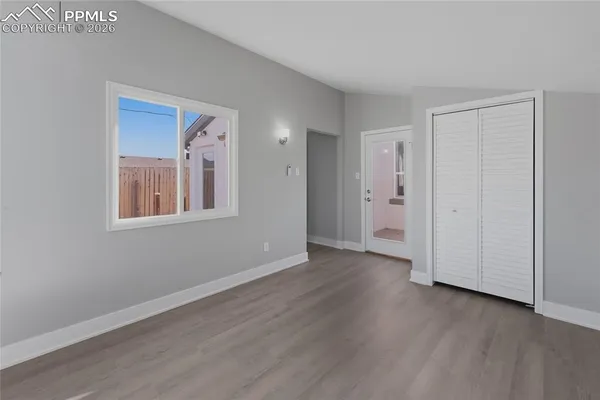 a view of an empty room with wooden floor and a window