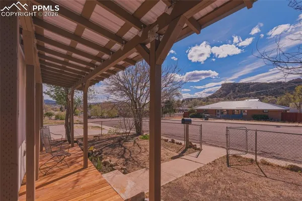 a view of a backyard with wooden floor and iron fence