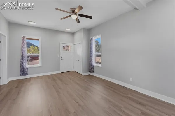 a view of empty room with wooden floor and ceiling fan