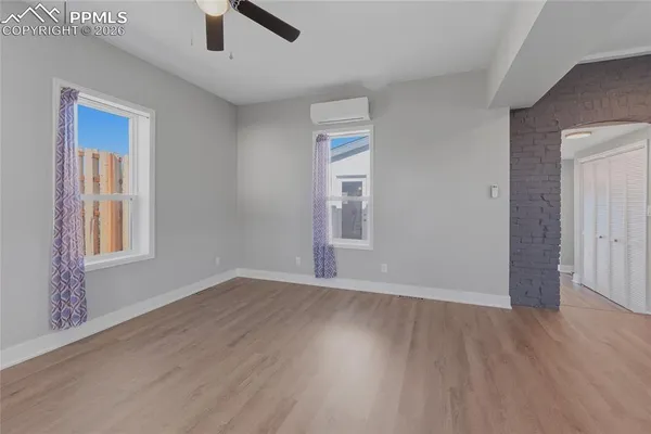 an empty room with wooden floor cabinet and windows