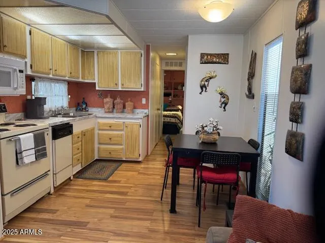 a kitchen with stainless steel appliances a stove a sink refrigerator and a dining table with wooden floor