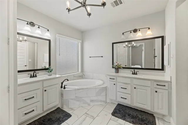 a bathroom with a double vanity sink a mirror and a bathtub
