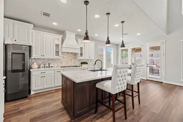 a kitchen with stainless steel appliances granite countertop a sink a stove a refrigerator and island with wooden floor