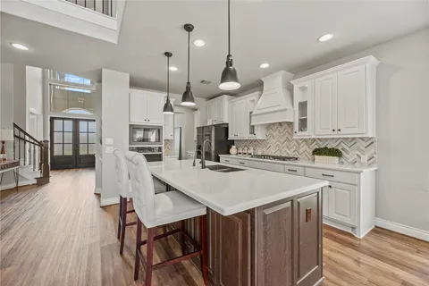 a kitchen with a table chairs wooden floors and a view of living room
