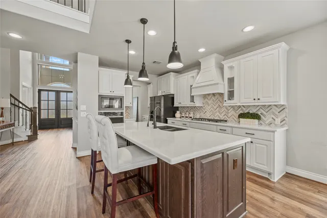 a kitchen with a table chairs wooden floors and a view of living room