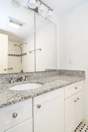 a bathroom with a granite countertop sink and white cabinets