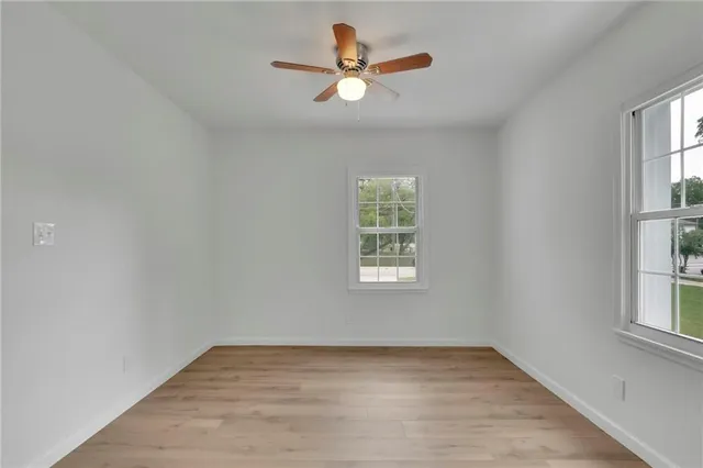 an empty room with window and ceiling fan