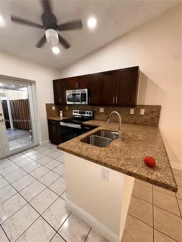 a kitchen with stainless steel appliances granite countertop a sink a stove and a refrigerator