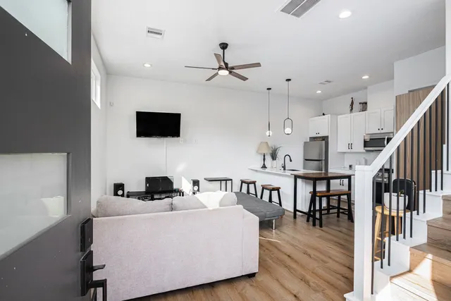 a living room with couches a coffee table and a flat screen tv with kitchen view