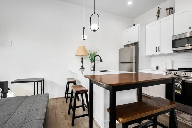 a kitchen with stainless steel appliances a table chairs and a microwave