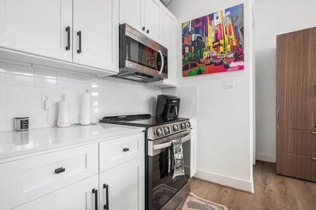 a kitchen with stainless steel appliances white cabinets and a stove top oven