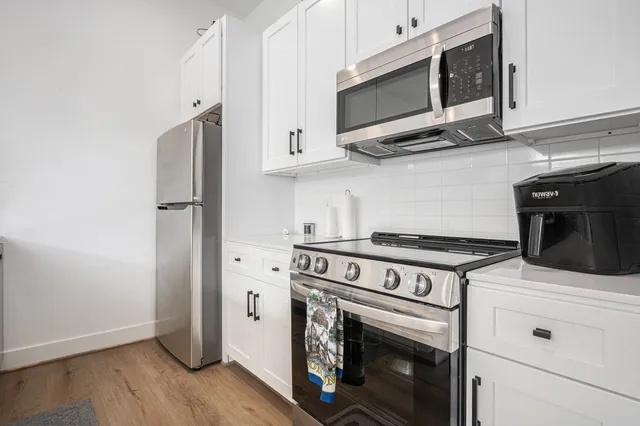 a kitchen with stainless steel appliances white cabinets and a stove top oven