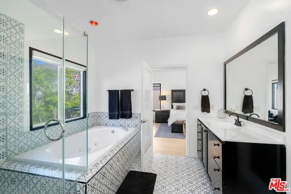a spacious bathroom with a tub sink and mirror