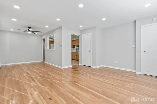 a view of an empty room with wooden floor and a bathroom