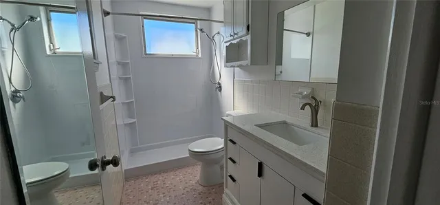 a bathroom with a granite countertop sink toilet and shower
