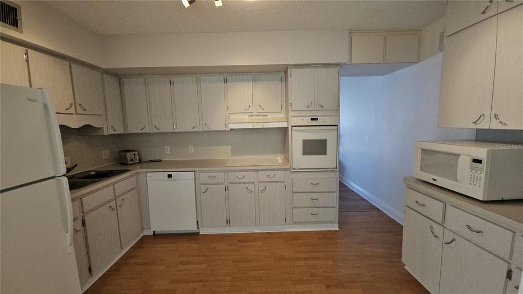 2450 Canadian Way, Unit 26 Clearwater, FL 33763 - Photo 25 of 32 a kitchen with granite countertop white cabinets and white appliances