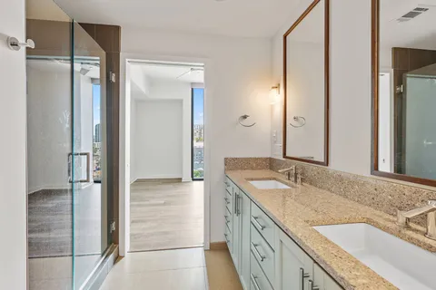 a bathroom with a granite countertop sink mirror and shower