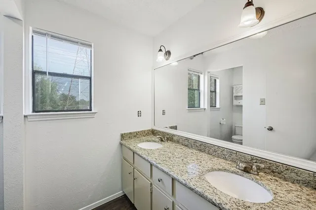 a bathroom with a granite countertop double vanity sink and mirror