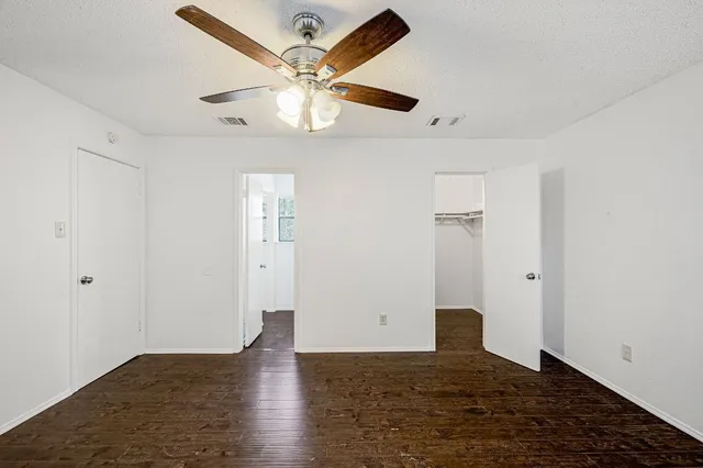 an empty room with wooden floor and ceiling fan