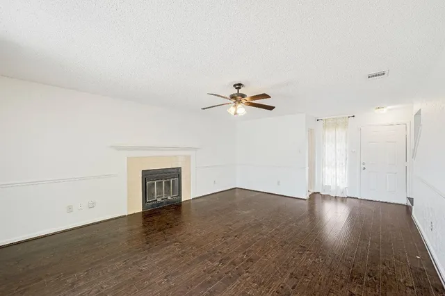 a view of an empty room with wooden floor and a fireplace