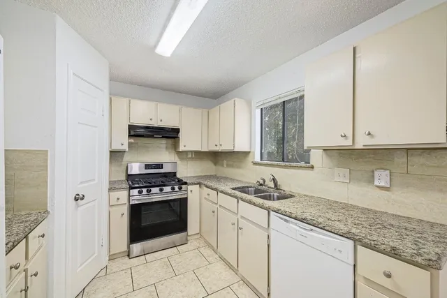 a kitchen with granite countertop a stove sink and cabinets